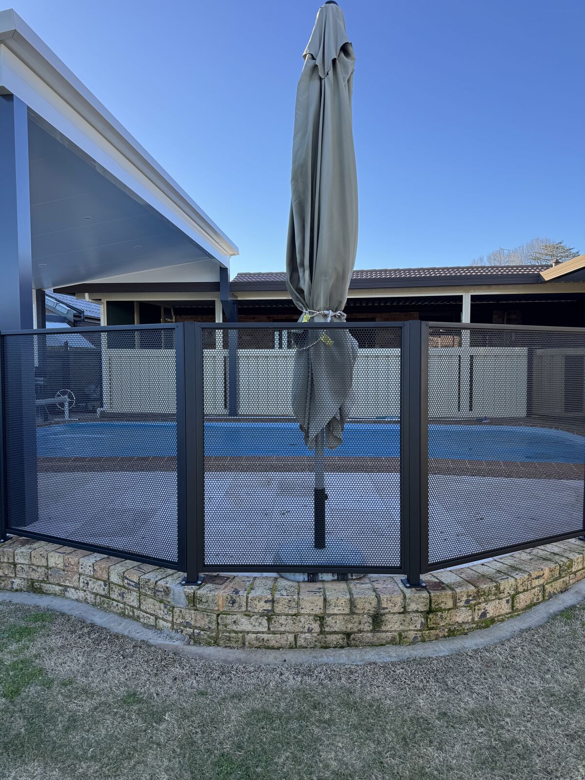 Pure Perf pool fence panels in Textured Black beside a swimming pool